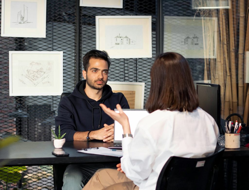 un homme assis à un bureau parlant à une femme